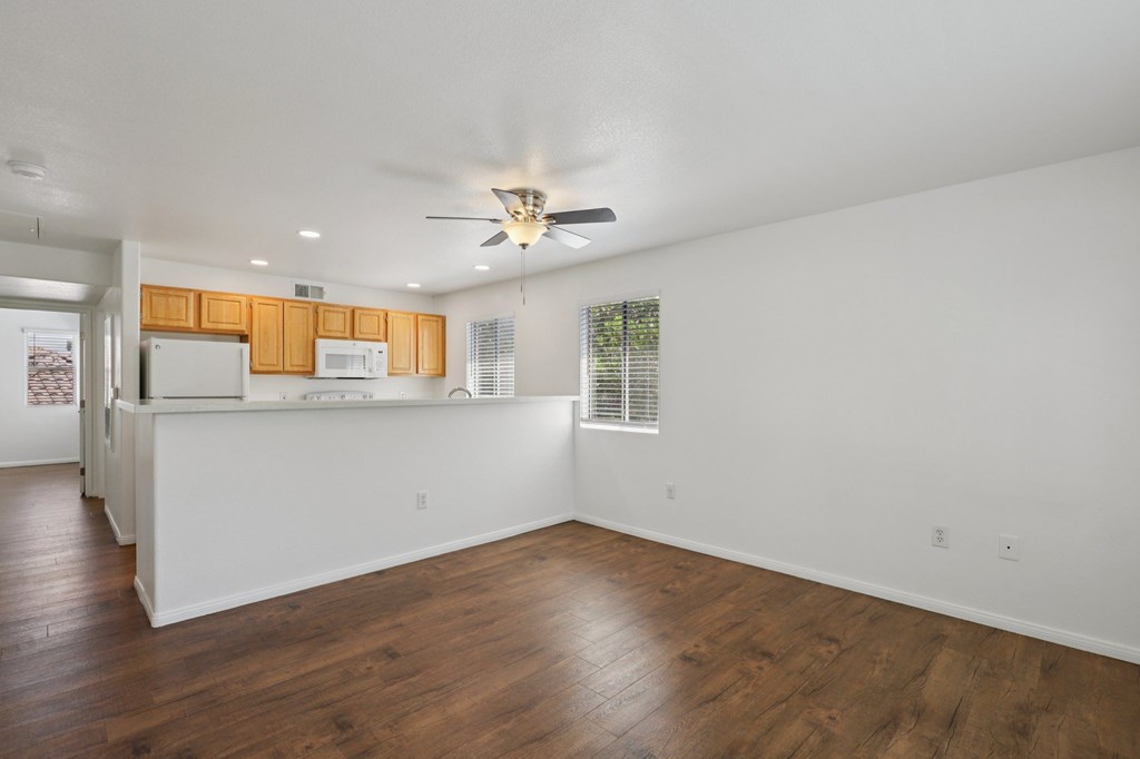 View of the kitchen and living room with wooden floors and white walls.