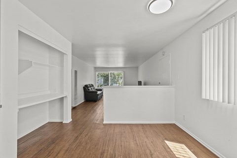 A room with white walls and wooden flooring with a window on the right side.