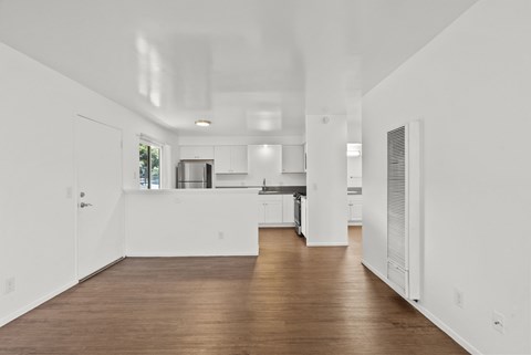 A spacious kitchen with white walls and wooden flooring.