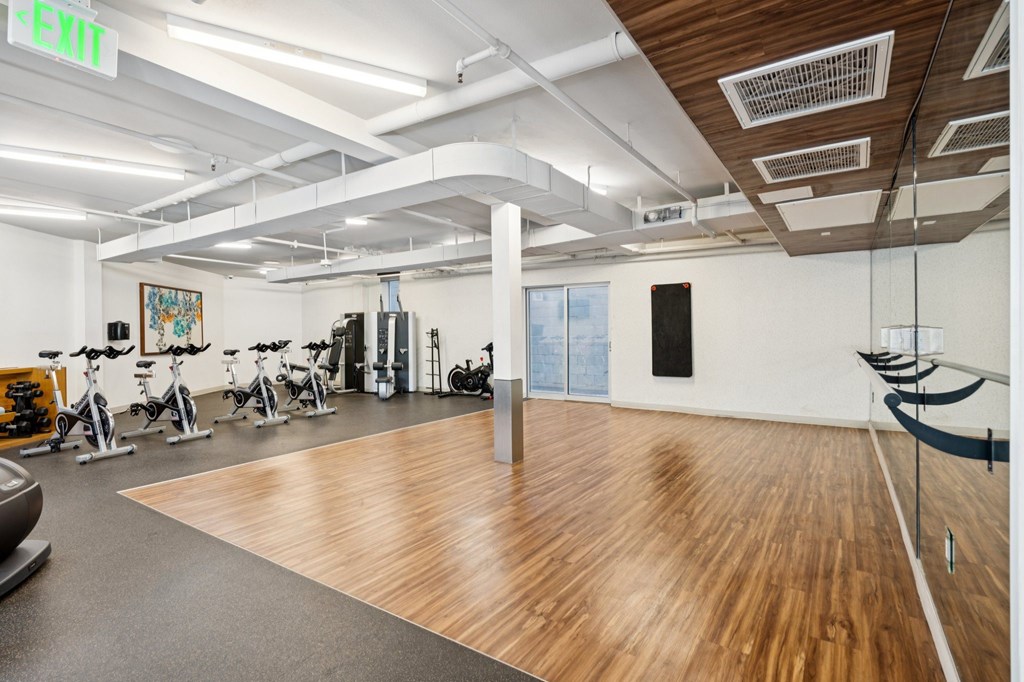 A gym with a variety of exercise equipment including treadmills, stationary bikes, and weights.