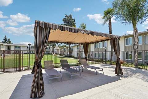 A patio with a striped canopy and chairs.