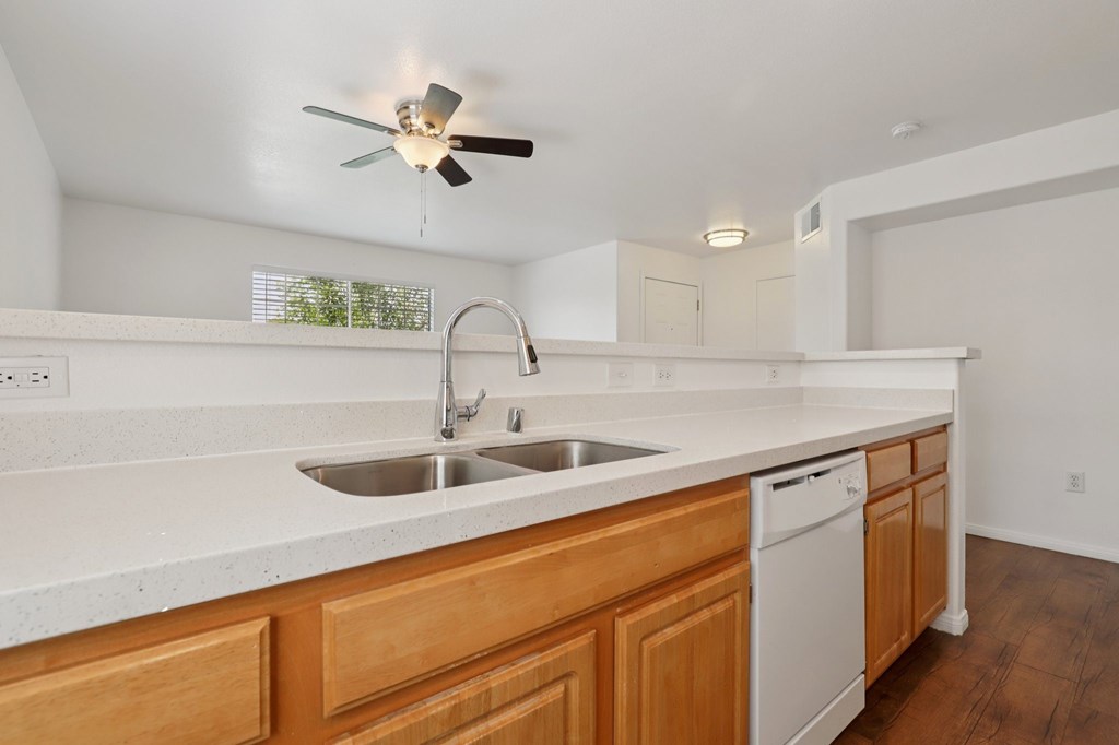A kitchen with a white counter top and wooden cabinets.