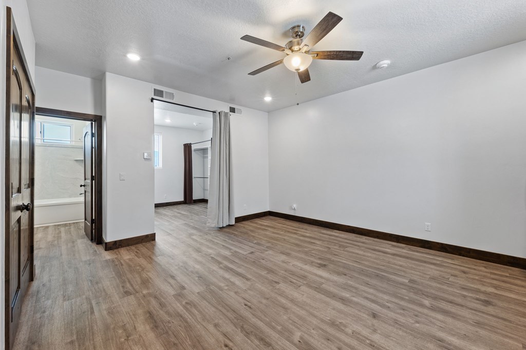 A room with a ceiling fan and wooden flooring.