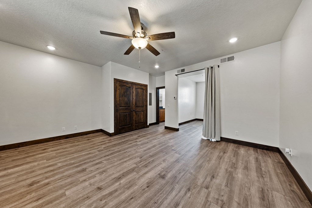 A room with a ceiling fan and wooden flooring.