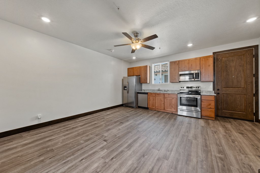 A kitchen with wooden floors and a ceiling fan.