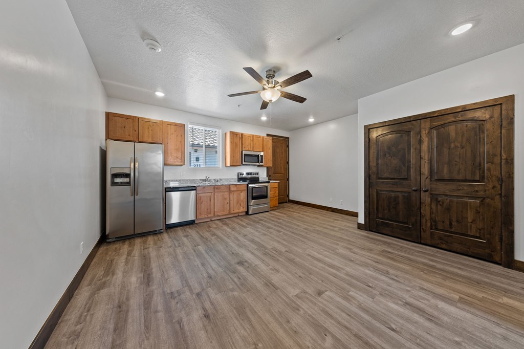 A kitchen with wooden floors and a ceiling fan.
