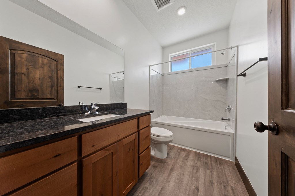A bathroom with a wooden vanity and a walk-in shower.