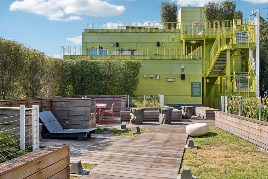 A green building with a yellow staircase and a wooden deck in front.