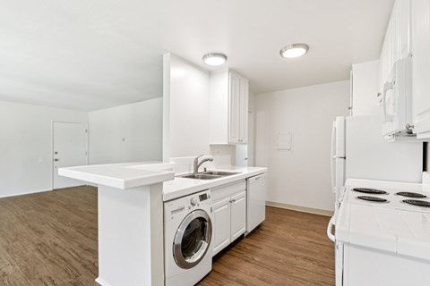 A white kitchen with a washing machine and a stove.