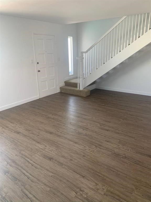 an empty living room with hard wood floors and a staircase