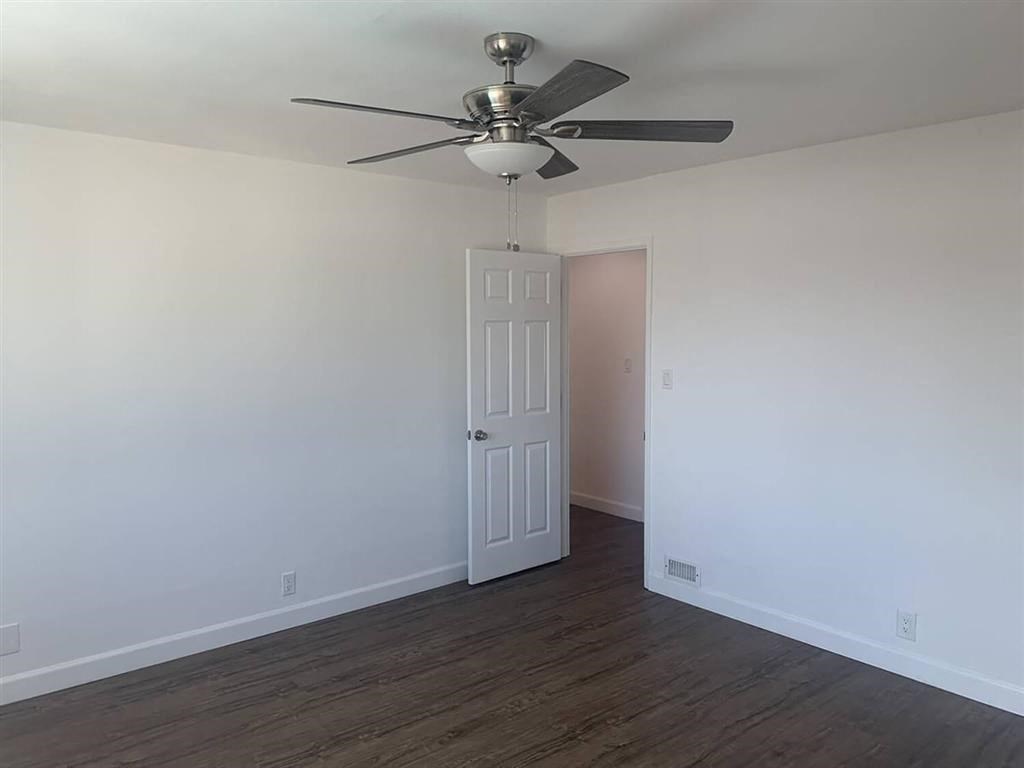an empty room with a ceiling fan and a door