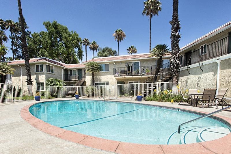 a swimming pool in front of a building with palm trees
