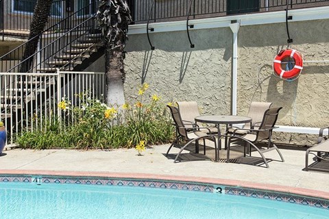 a table and chairs next to a swimming pool