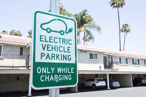 a green and white electric vehicle parking only while charging sign