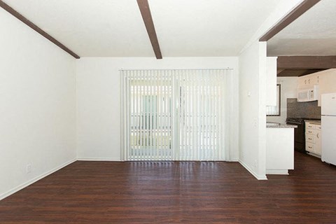 an empty living room with a door to a kitchen