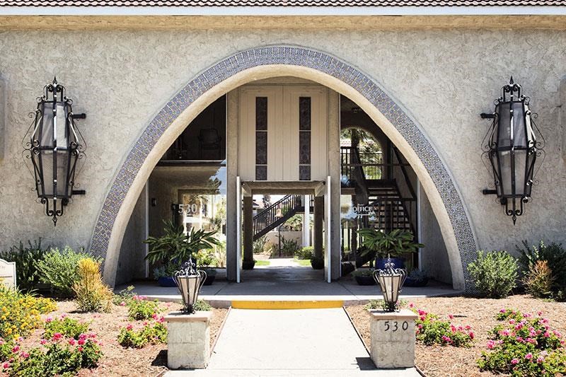 the front entrance of a building with two lamps and a walkway