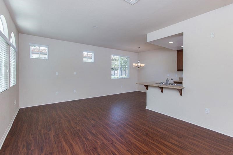 an empty living room and kitchen with wood floors