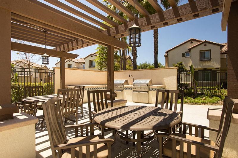 a patio with tables and chairs and a grill