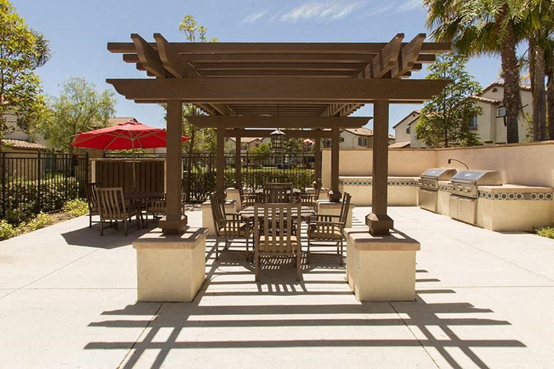 a patio with a table and chairs under a wooden pavilion