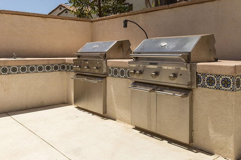 two stainless steel barbecue grills on a patio