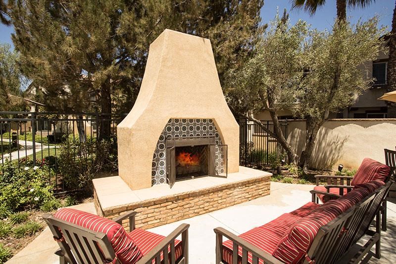 a backyard with a stone fireplace and patio furniture