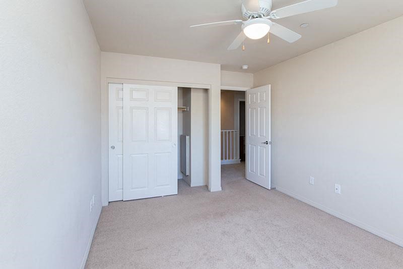 an empty living room with a ceiling fan