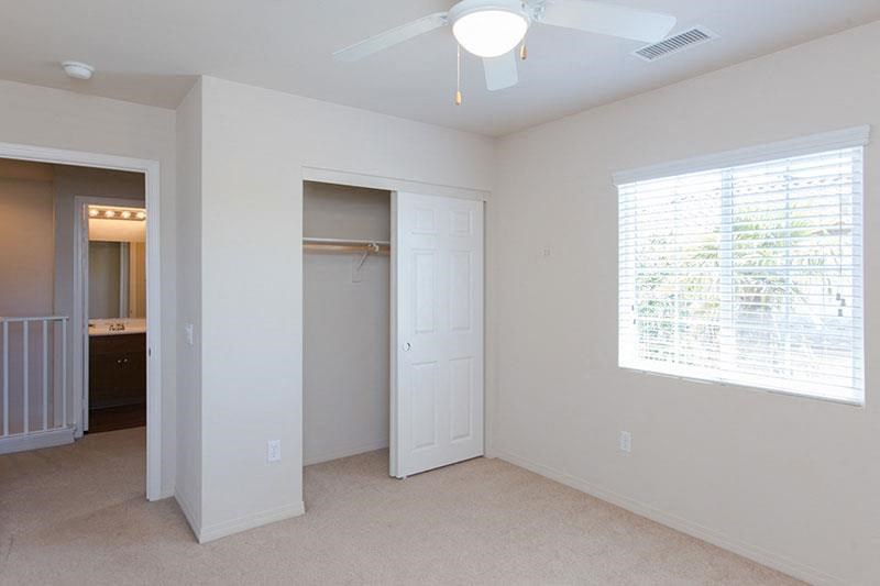 an empty bedroom with a ceiling fan and a closet