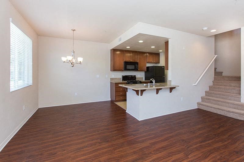 an empty living room with a kitchen and stairs