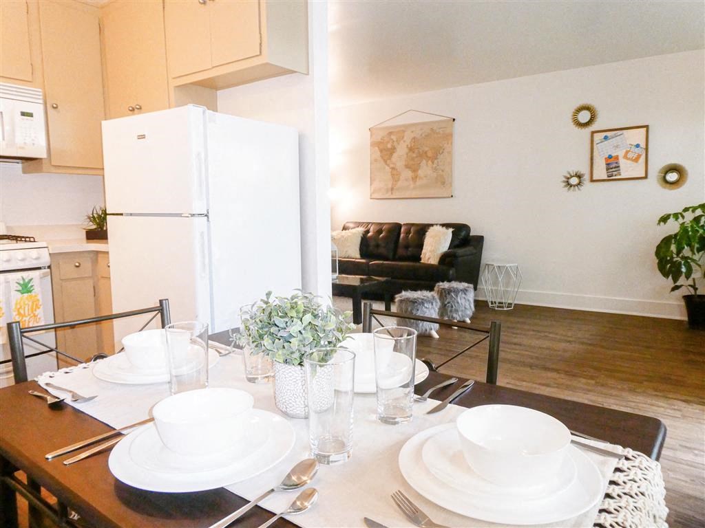 a dining room and living room with a table and a refrigerator