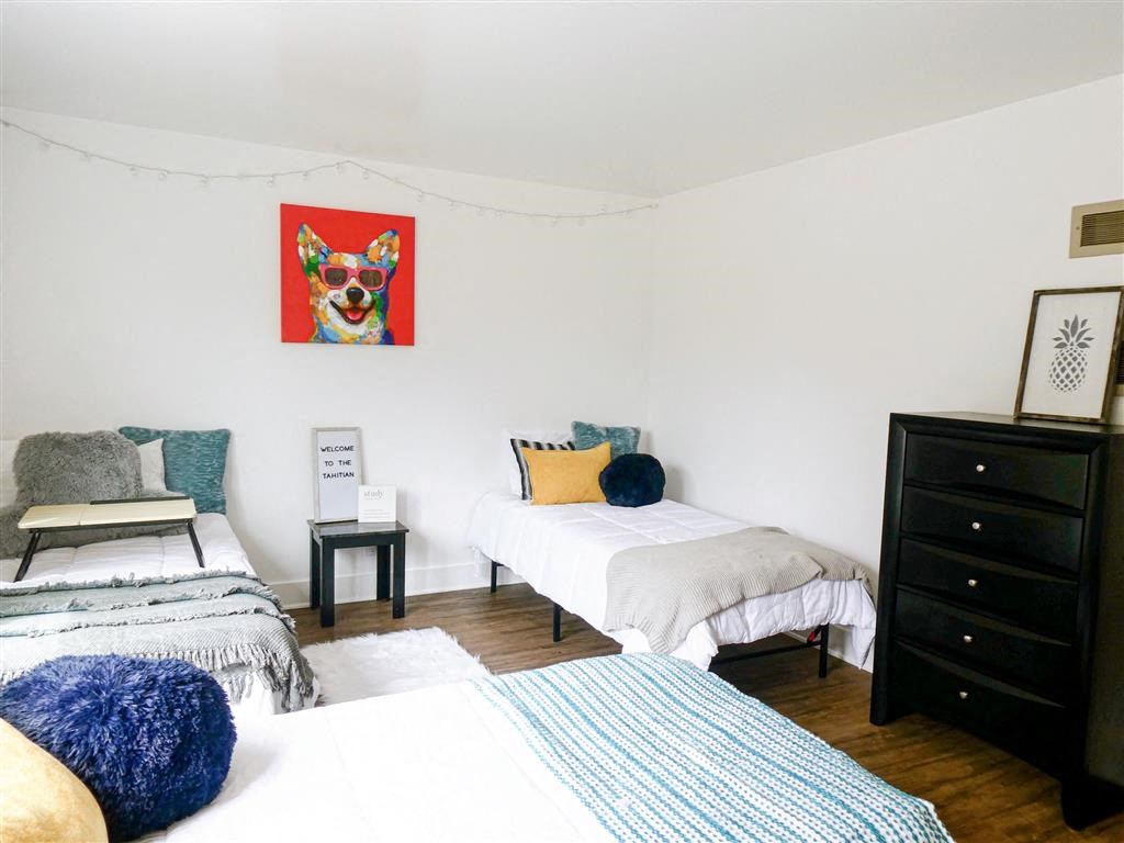 a bedroom with two beds and a painting of a dog on the wall