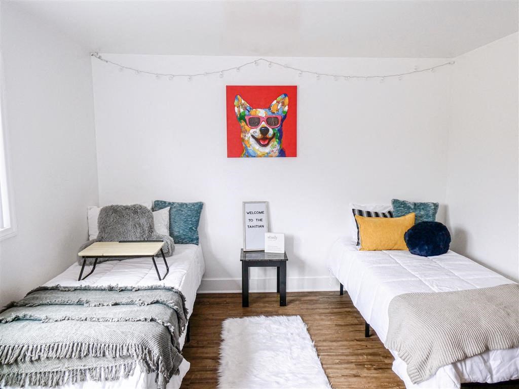 a bedroom with two beds and a painting of a dog on the wall