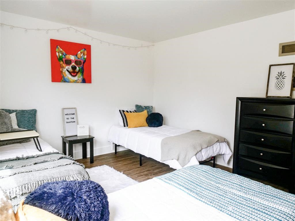 a bedroom with two beds and a painting of a dog on the wall