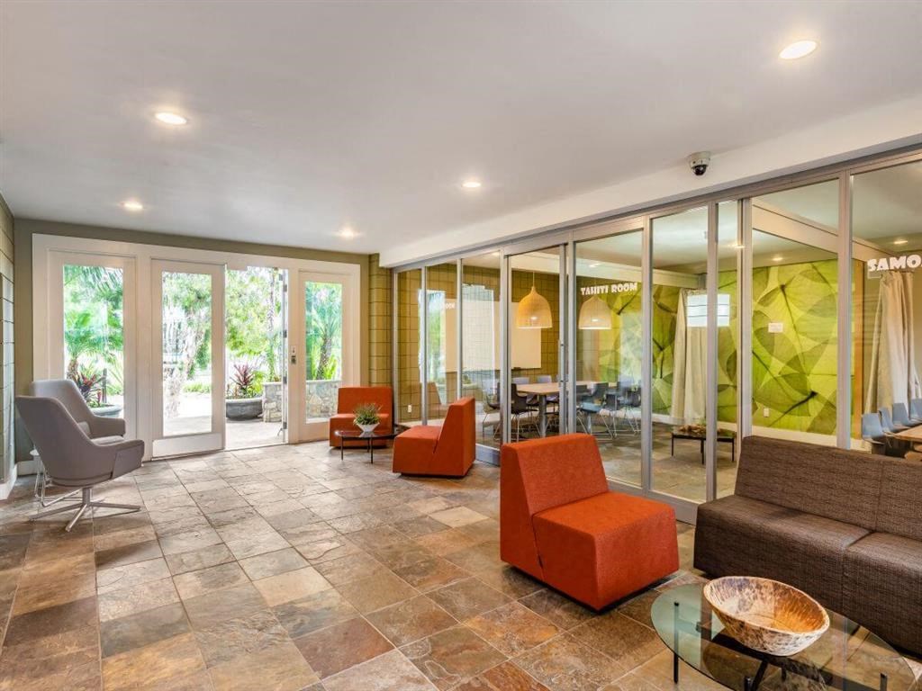 a living room with orange furniture and glass walls