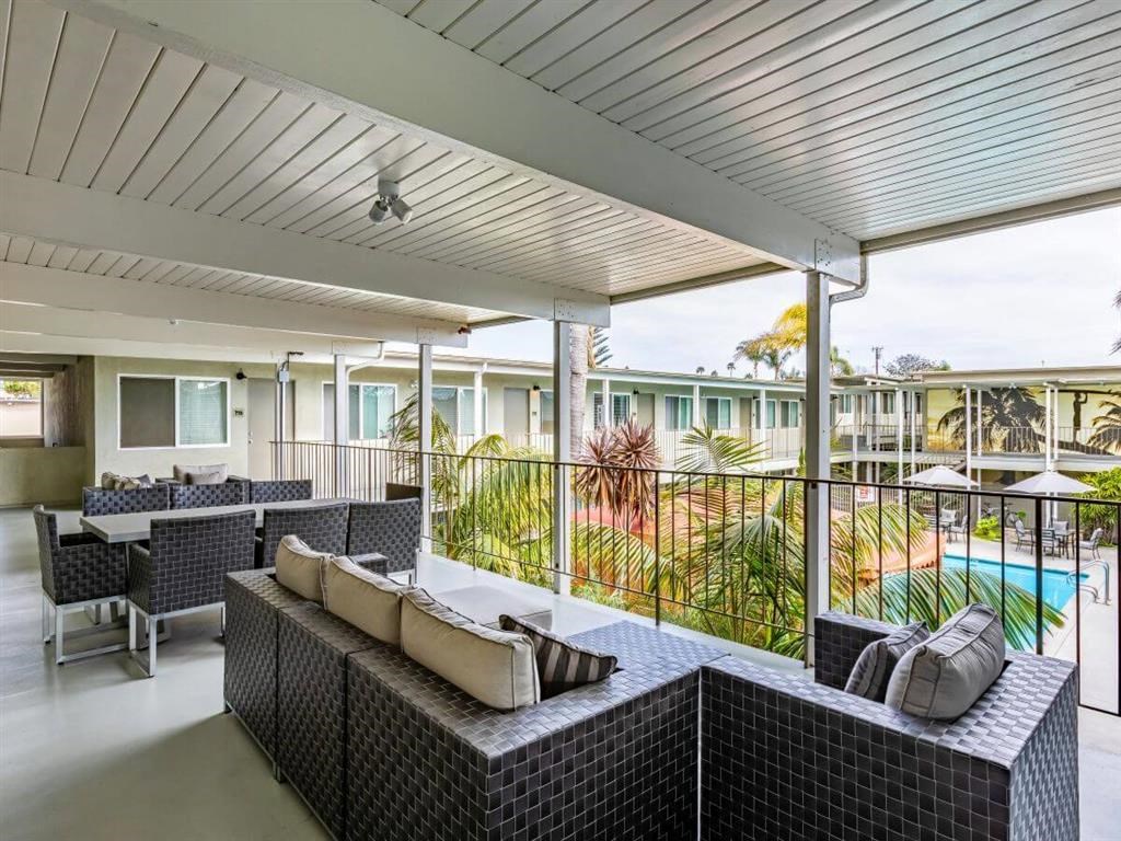a covered patio with tables and chairs and a pool