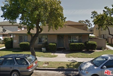 A house with a tree in front of it and two cars parked in front of the house.