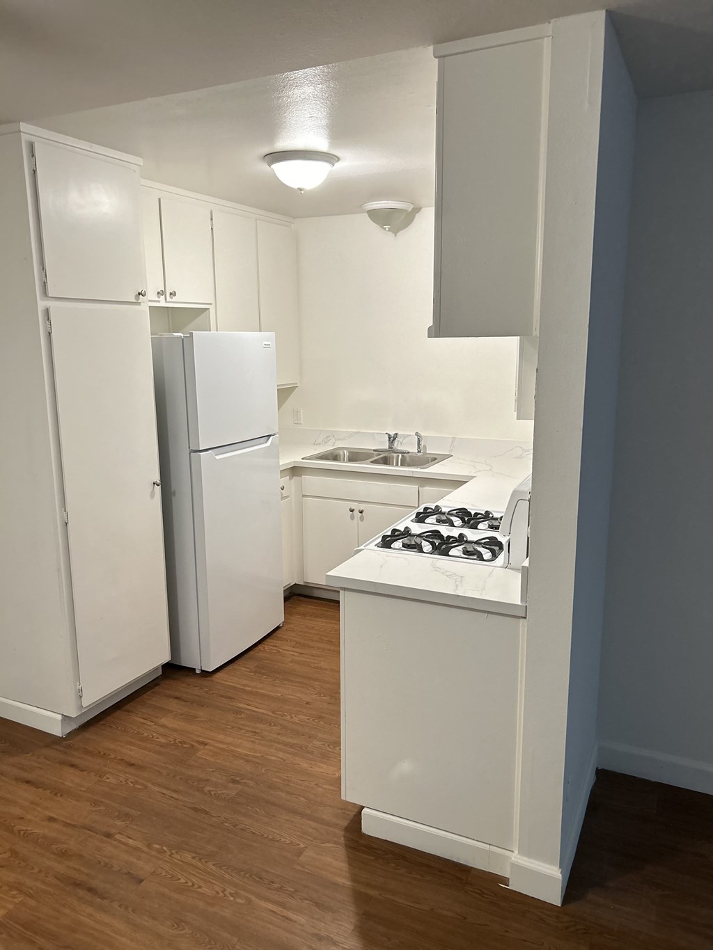 A small kitchen with a sink, stove and refrigerator.