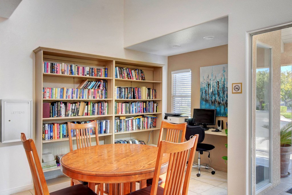 a library with a table and business center in the clubhouse