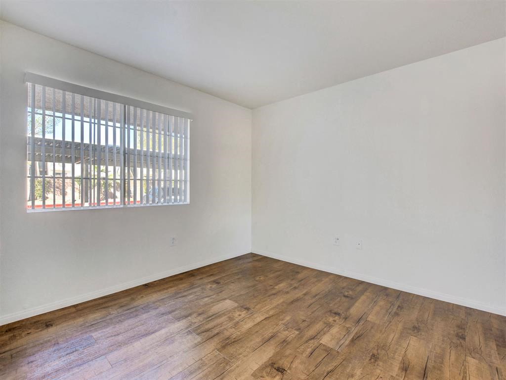 a bedroom with hardwood floors and a large window