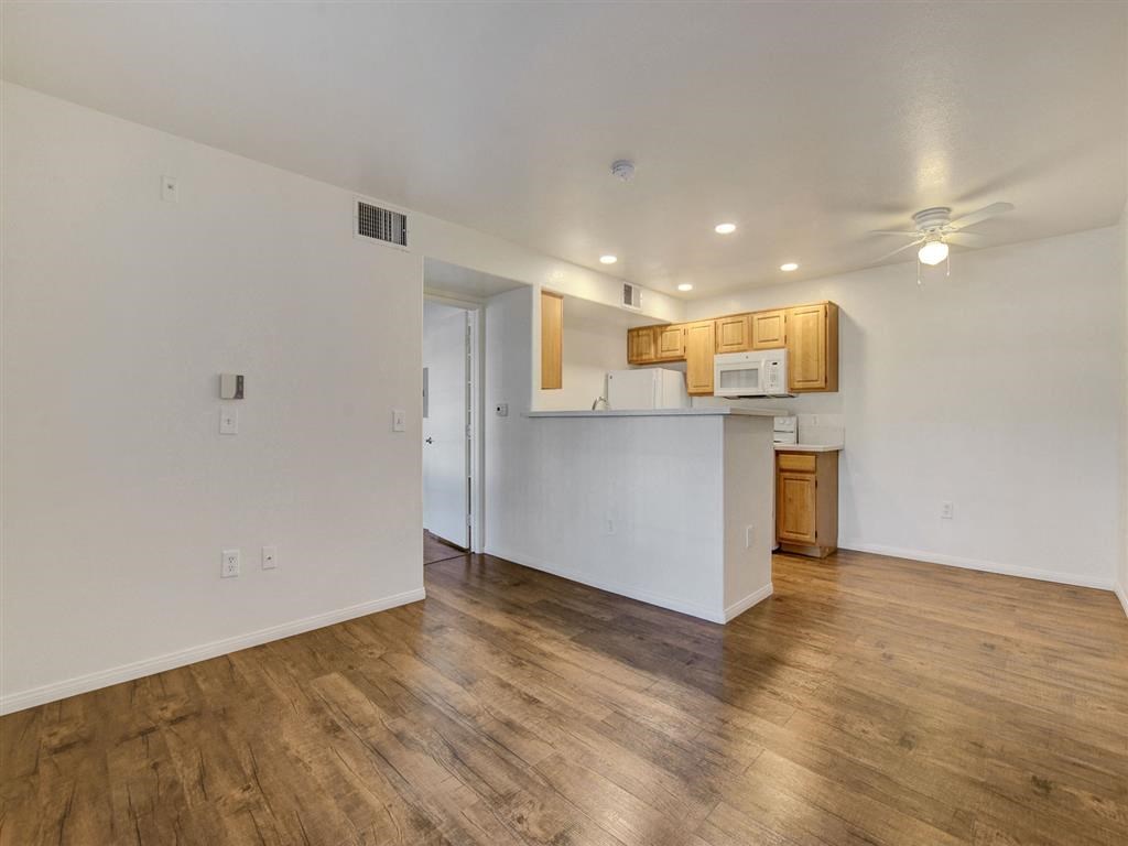 an empty living room with a kitchen in the background