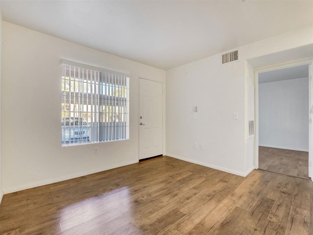 a bedroom with hardwood floors and a large window