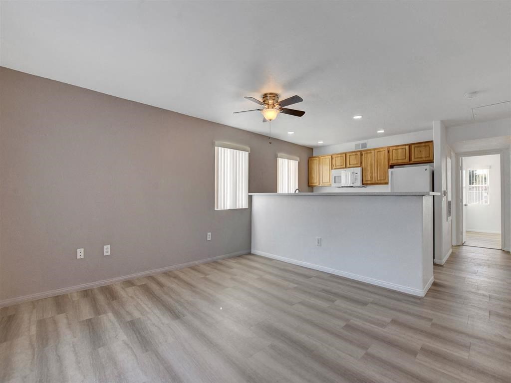 an empty living room with a ceiling fan