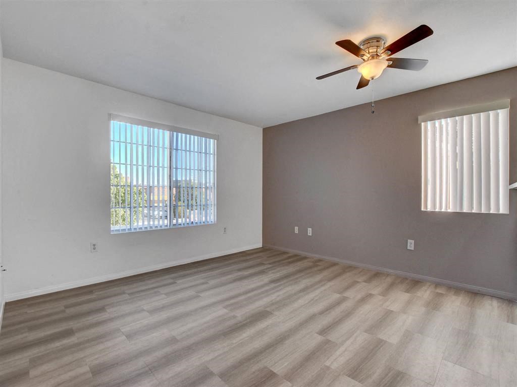 an empty living room with a ceiling fan and two windows