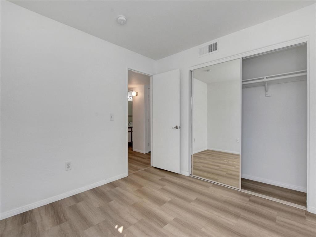 a bedroom with white walls and a wooden floor