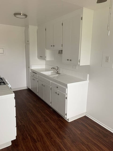 an overhead view of a white kitchen with white cabinets and a wood floor