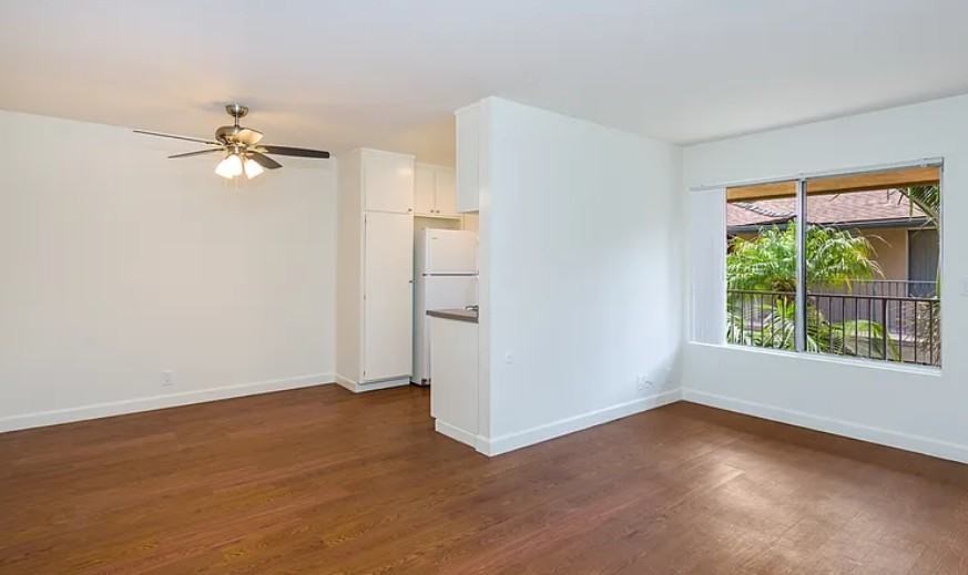A living room with a ceiling fan and wooden flooring.