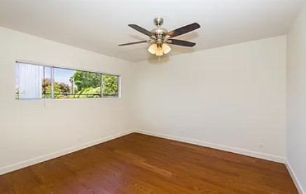 A bedroom with a ceiling fan and a window.
