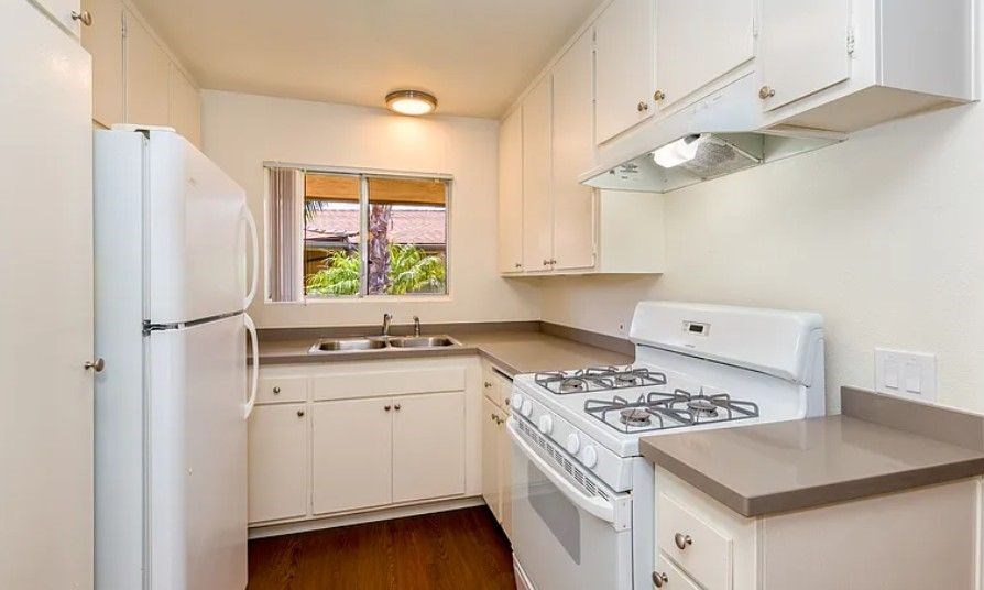 A kitchen with white appliances and cabinets.