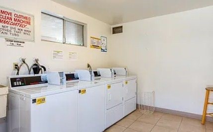 A laundromat with several washing machines and a sign on the wall.