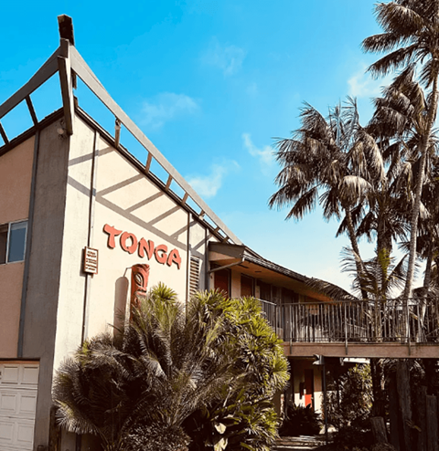 A building with a sign that says "TONGA" in front of some trees.