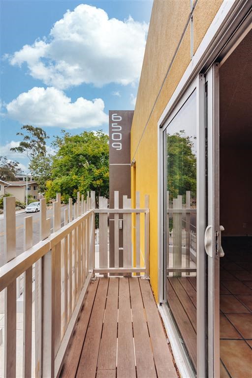 a balcony with a wooden floor and a glass door